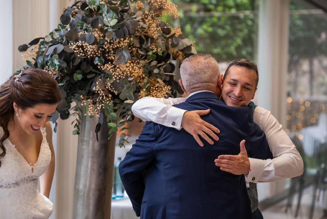 Paco abraza a un invitado mientras Rosi sonríe durante la celebración de su boda.