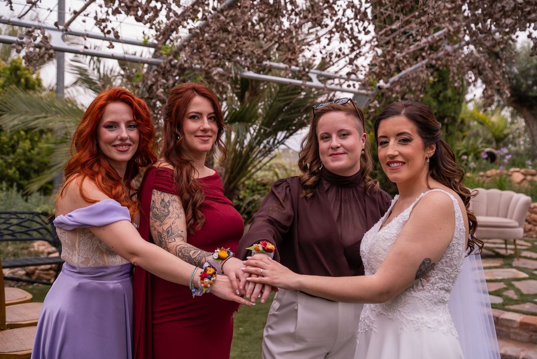 Rosi y tres invitadas muestran sus pulseras de flores durante la boda.