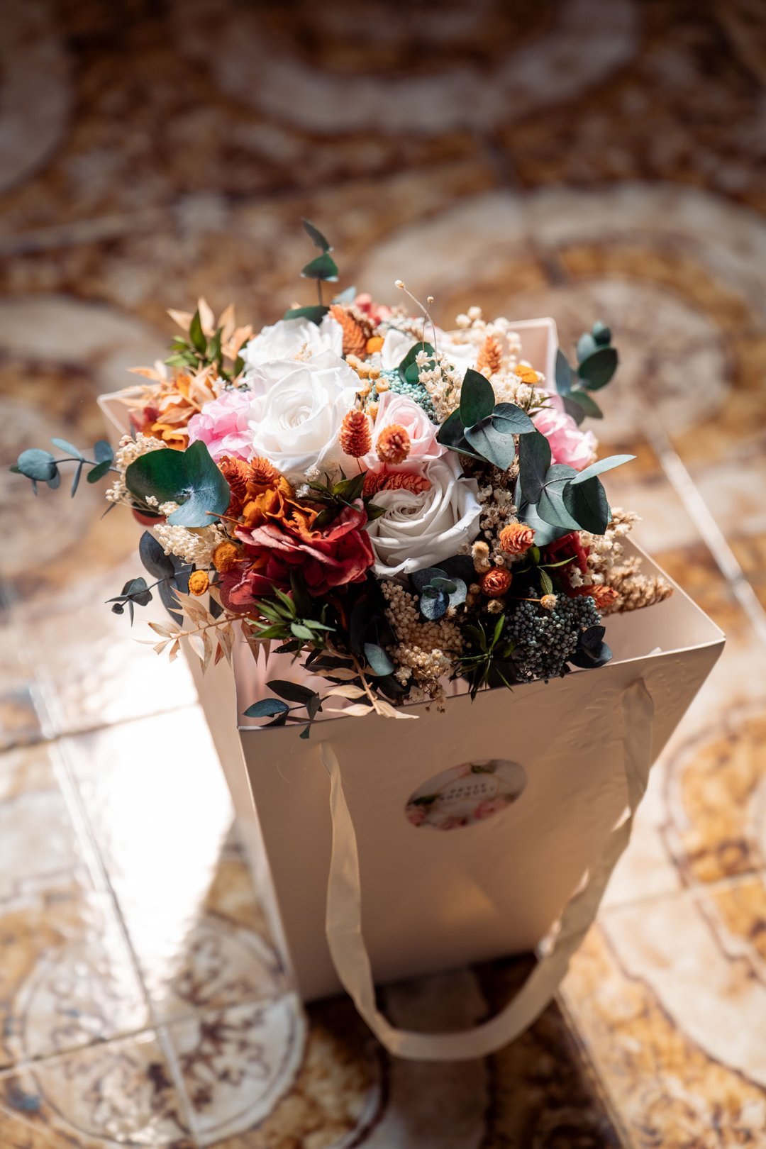 Ramo de novia con rosas blancas y rosas, flores anaranjadas y eucalipto.