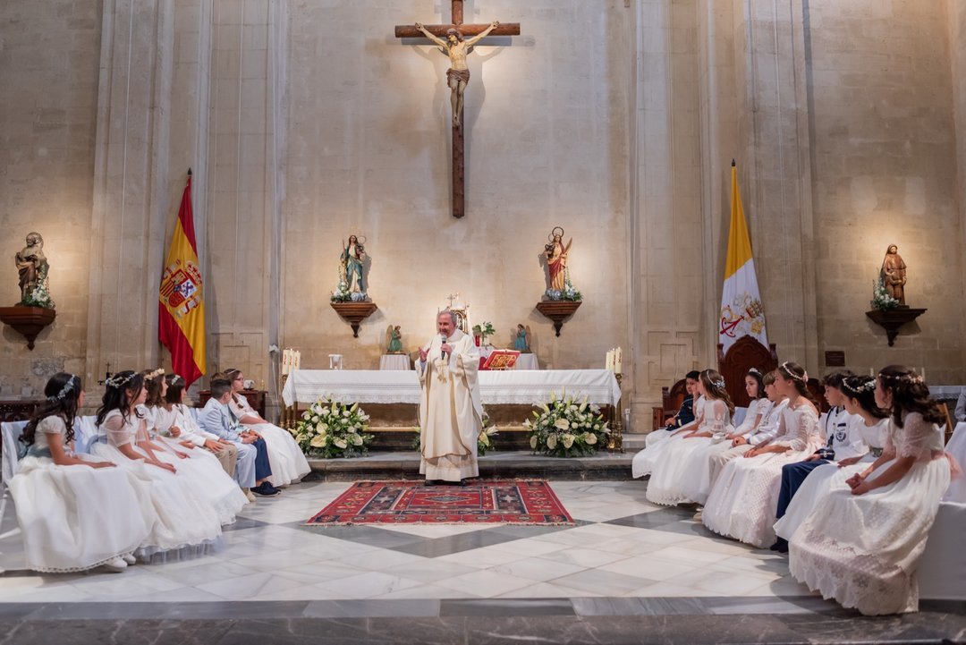 Niños sentados a ambos lados del altar durante su primera comunión