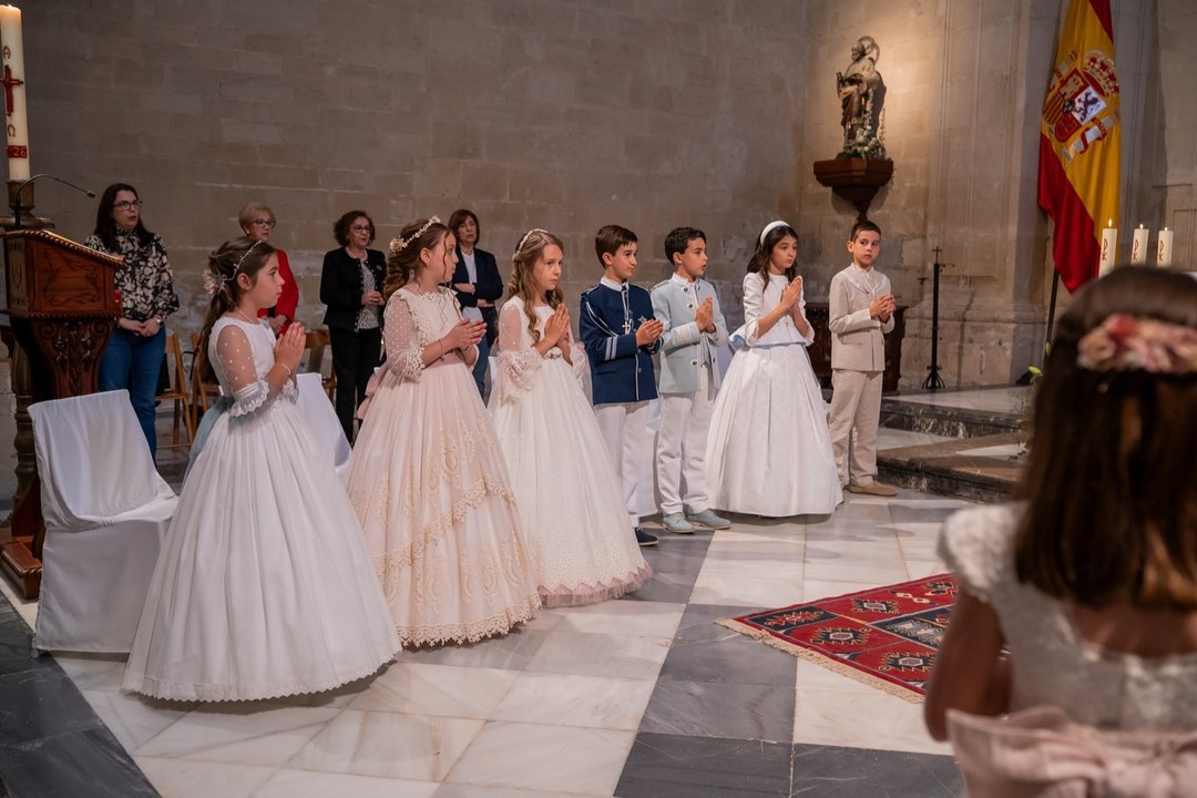 Niños de comunión con las manos juntas junto al altar