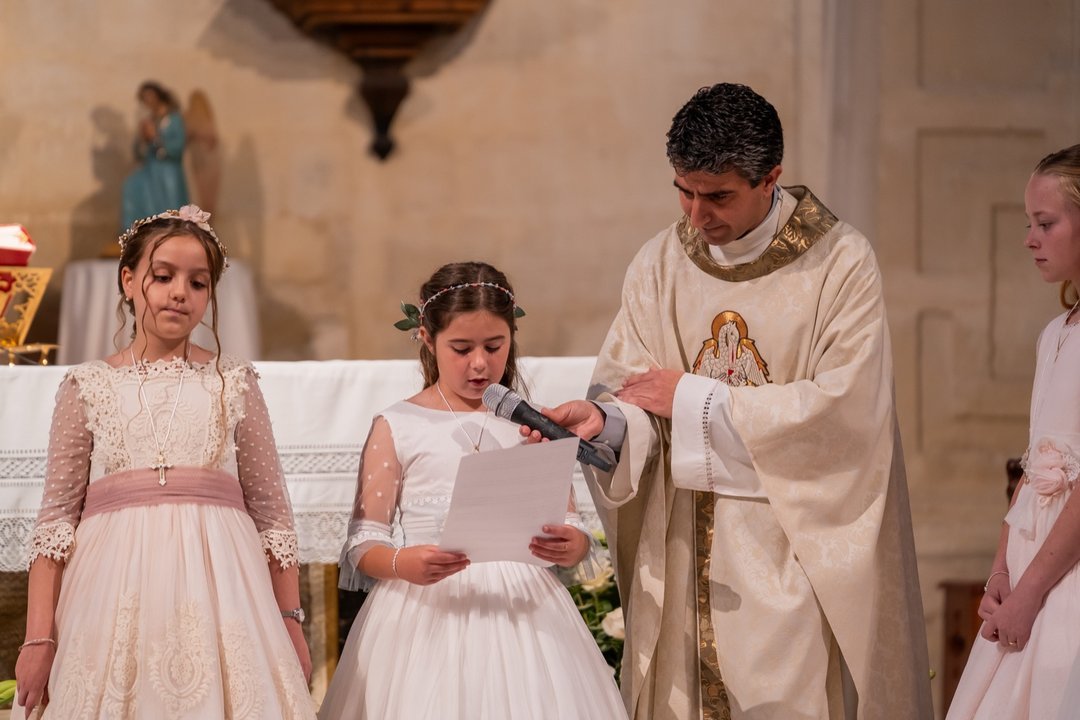 Niña realizando una lectura con el sacerdote durante la comunión