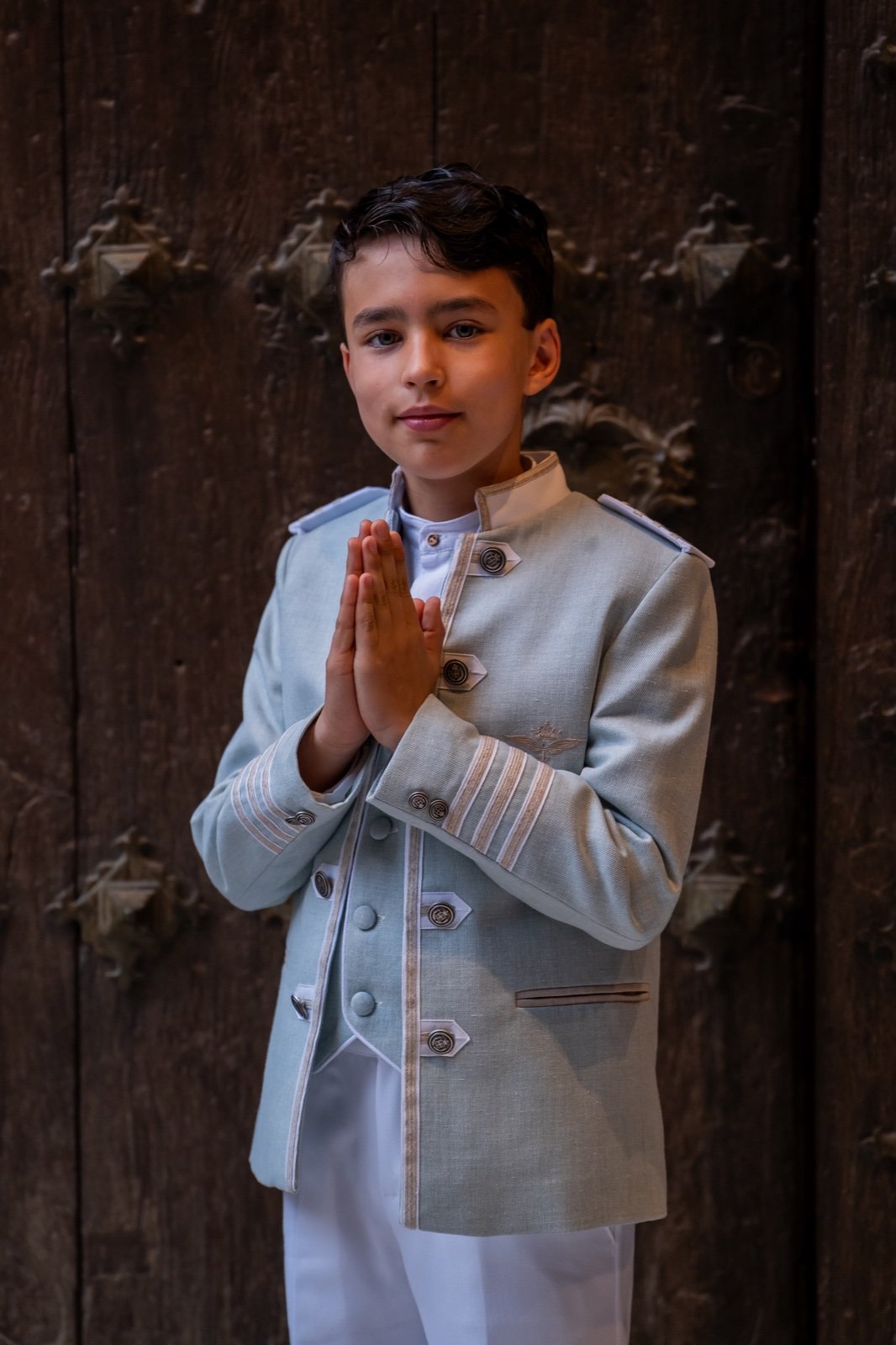 Niño con traje azul de comunión y las manos juntas