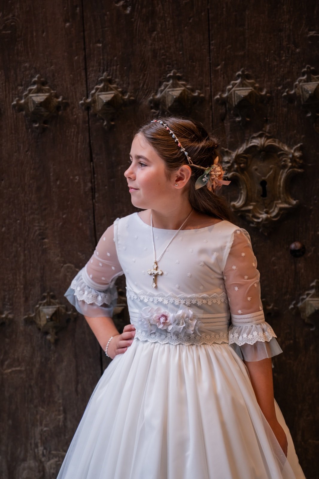 Retrato de una niña de comunión junto a una puerta de madera