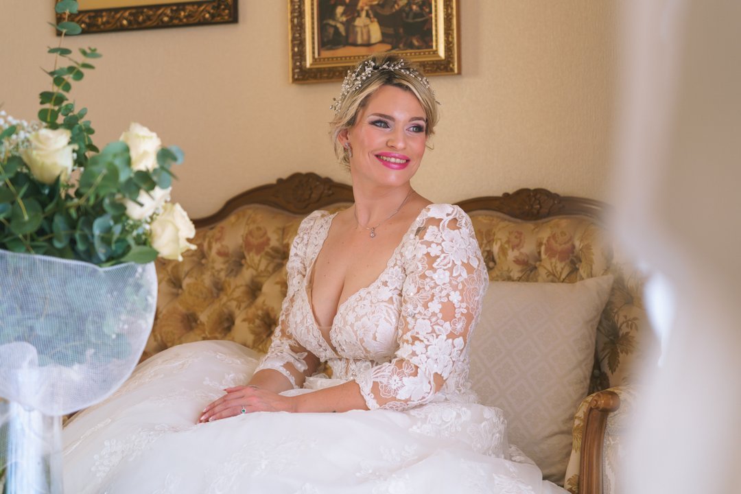 Una novia con vestido de encaje sentada en un sofá.