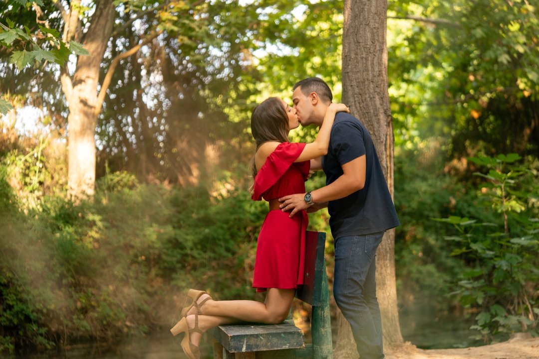Soraya y Paco se besan junto a un árbol y una valla de madera durante su preboda.