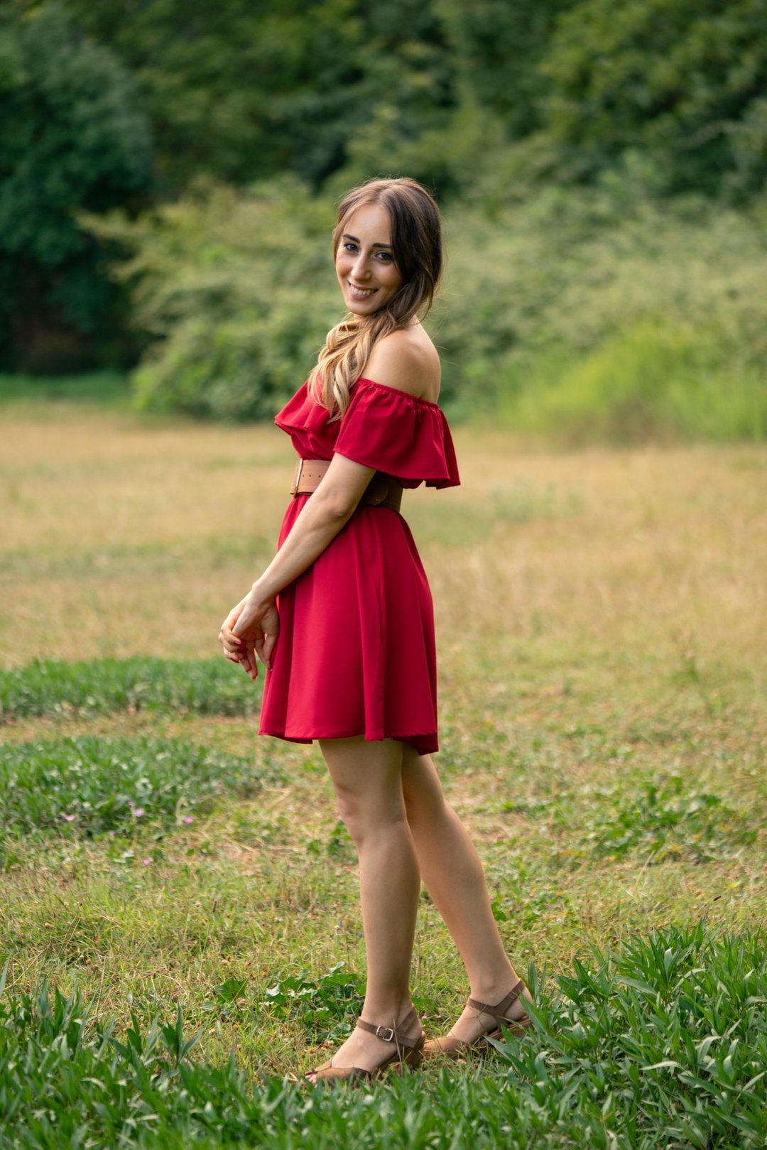 Soraya con vestido rojo en un prado durante su sesión de preboda.