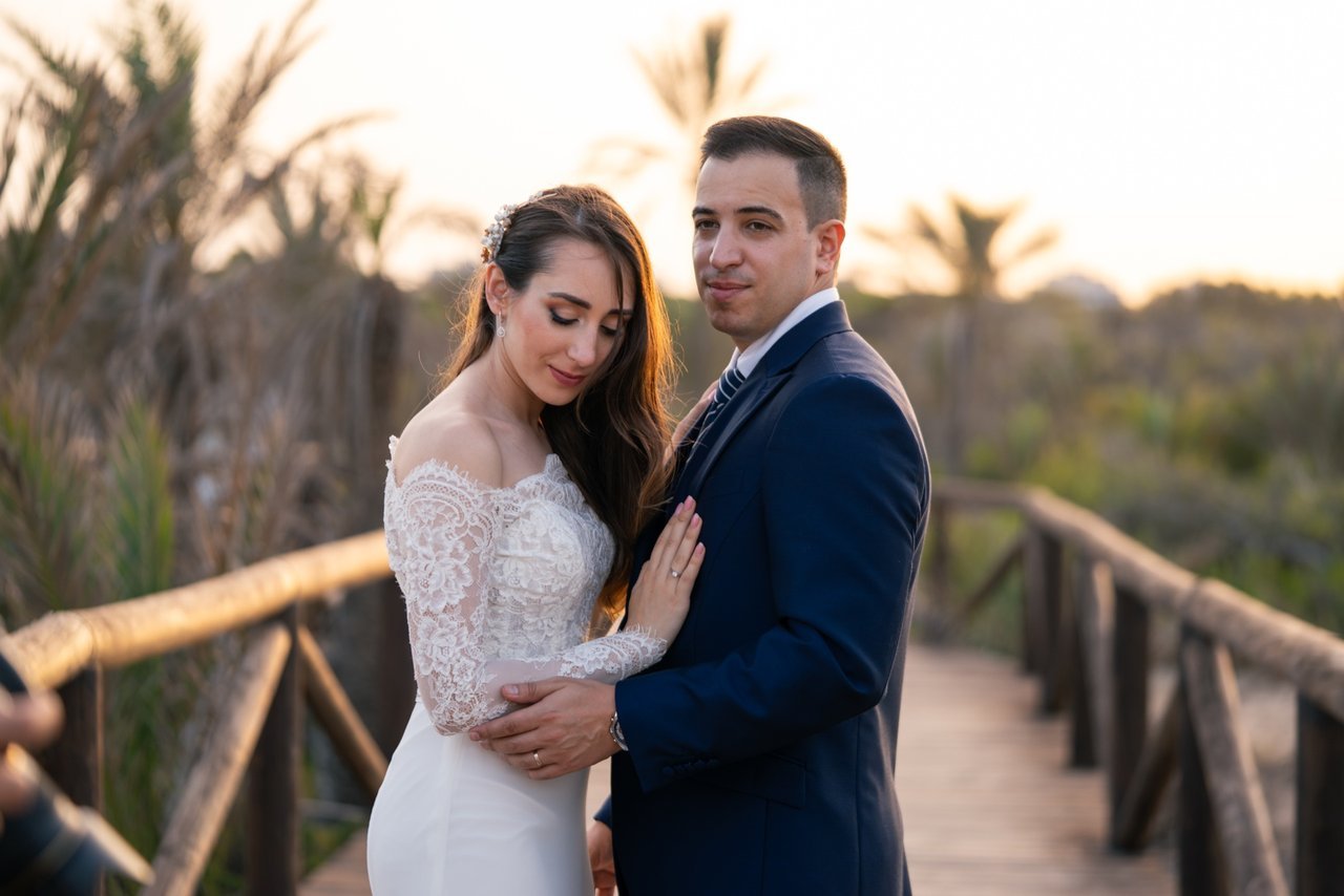 Soraya y Paco abrazados en una pasarela de madera al atardecer durante su reportaje de boda.