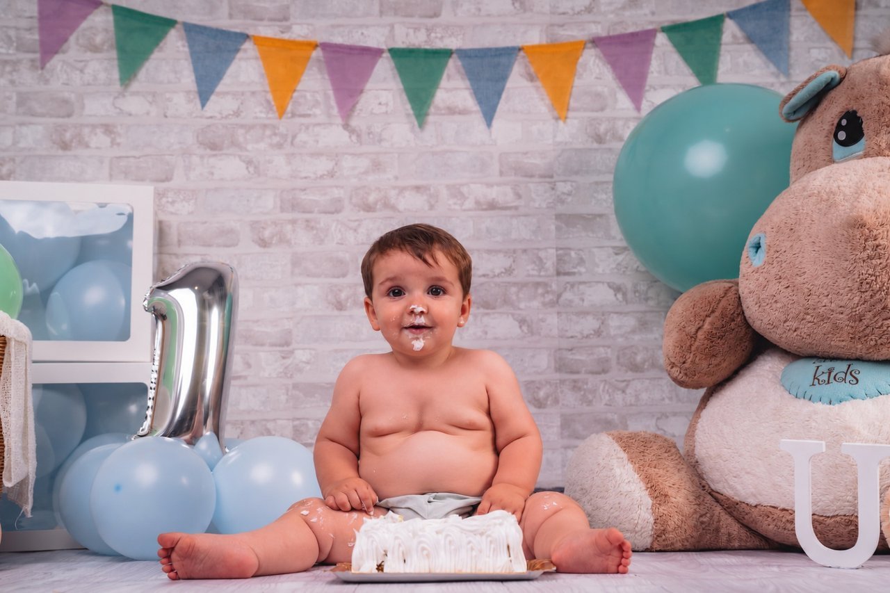 Bebé con tarta de cumpleaños, globos y banderines en una sesión Smash Cake
